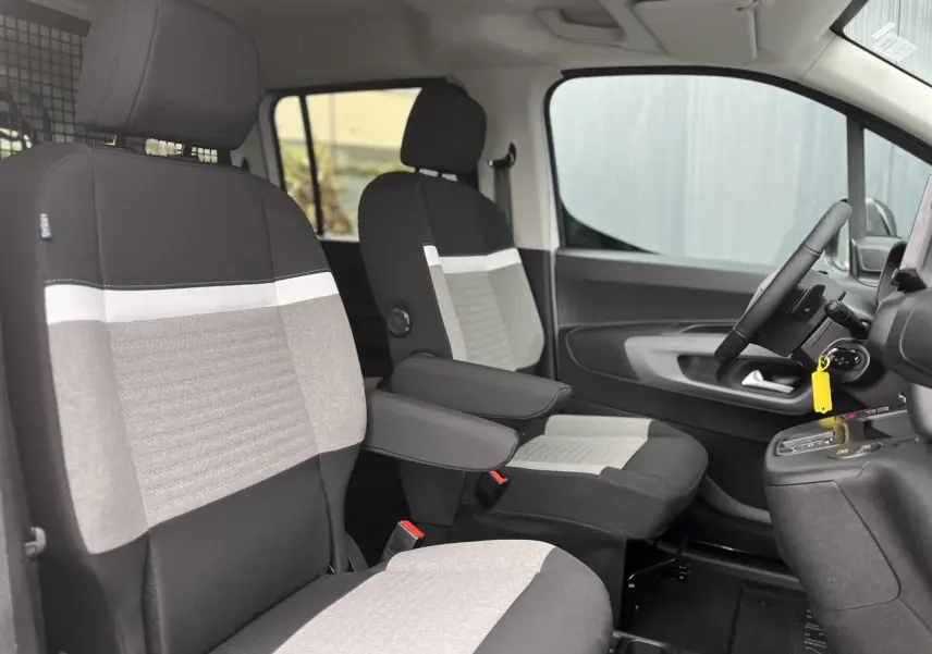 Vue intérieure côté conducteur du Citroën Berlingo Multispace 2025, sièges tissu bicolore avec accoudoirs et volant multifonctions.