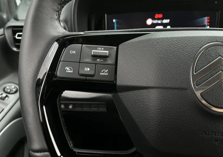 Gros plan sur le volant cuir noir du Citroën Berlingo Multispace 2025, avec commandes multifonctions à gauche.