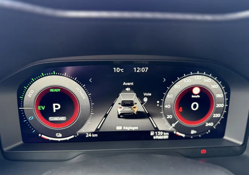 Affichage numérique du tableau de bord du Nissan Juke rouge Fuji, montrant la vitesse à 0 km/h et l'indicateur hybride en mode parking.