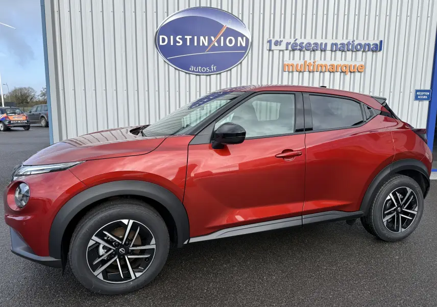 Nissan Juke 1.6 Hybrid rouge Fuji en profil côté gauche, avec jantes alliage noires et détails noirs contrastants.