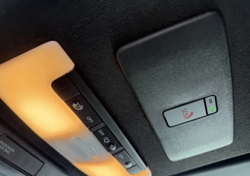 Gros plan sur la console de plafonnier intérieur avec éclairage orange et bouton SOS du Nissan Juke rouge Fuji 2025.