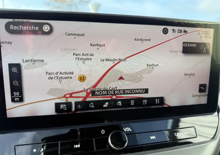 Écran tactile du système de navigation du Nissan Juke rouge Fuji, affichant une carte routière avec options et commandes intégrées.