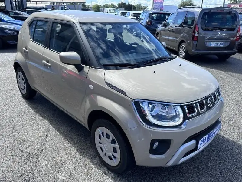 Suzuki Ignis beige vue 3/4 avant droit, compact et urbain avec phares LED et calandre chromée distinctive.