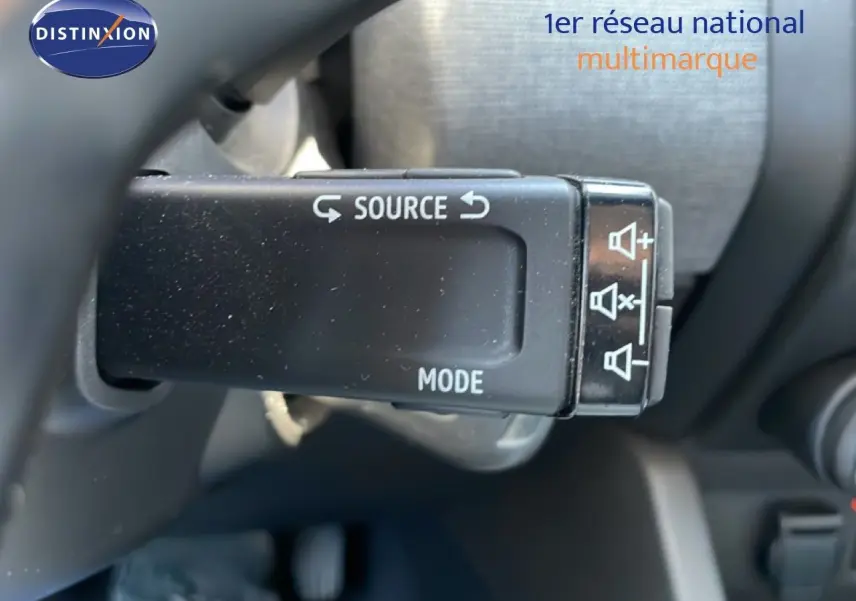 Gros plan sur la commande au volant de la Renault Clio noire, avec boutons source et mode visibles.