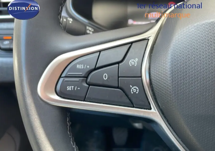 Gros plan sur les commandes au volant à gauche de la Renault Clio noire Étoile Metal, montrant les boutons de régulateur de vitesse.