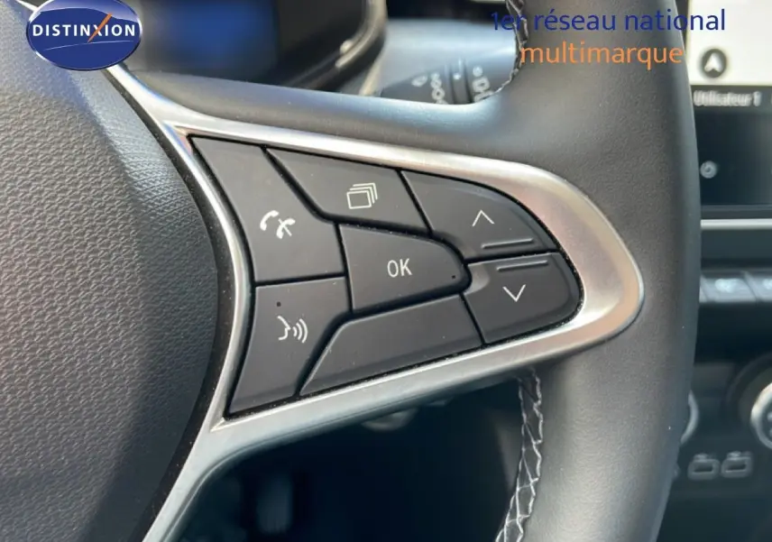 Gros plan sur les commandes multifonctions à gauche du volant cuir de la Renault Clio noire étoile métal 2025.