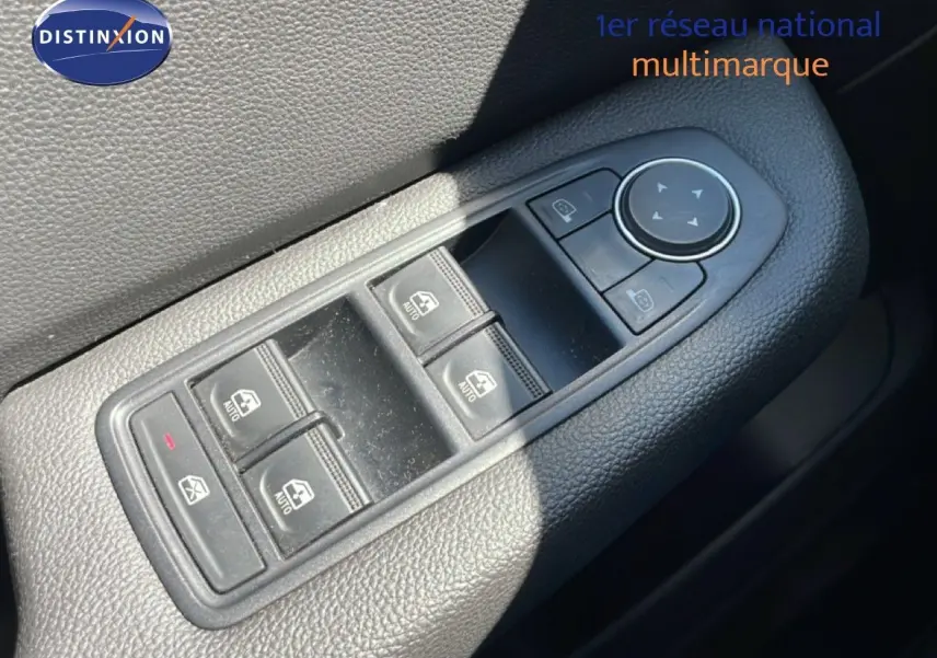 Gros plan sur les commandes des vitres électriques et des rétroviseurs sur la porte côté gauche d’une Renault Clio noire.