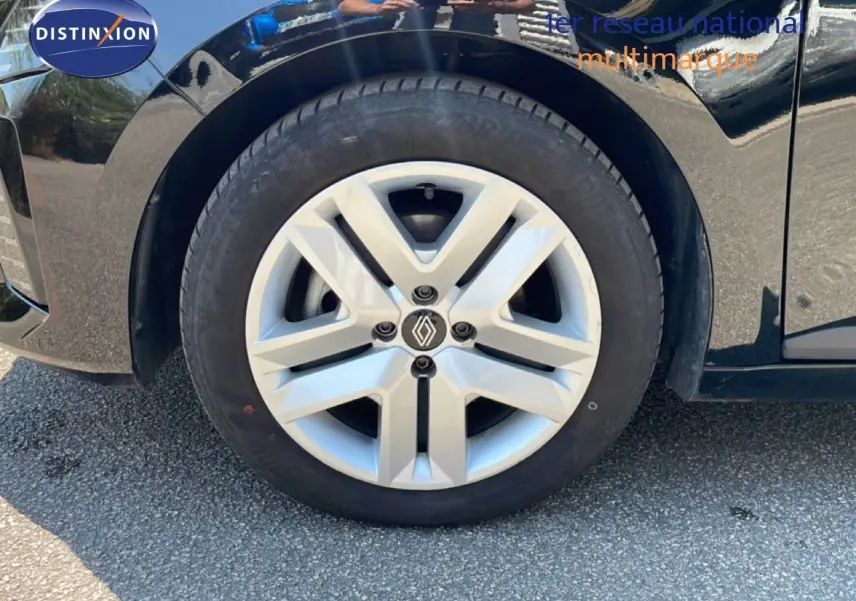 Gros plan sur la roue avant gauche d'une Renault Clio noire étoile métal, mettant en valeur la jante argentée au logo Renault.