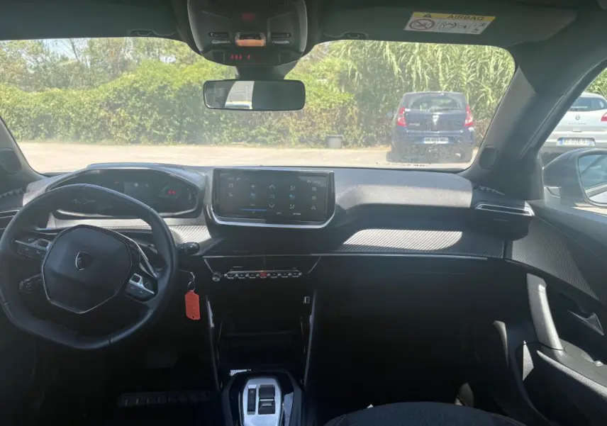 Vue intérieure avant du Peugeot 2008 Hybrid 145 gris, mettant en valeur le cockpit numérique et l'écran tactile central.