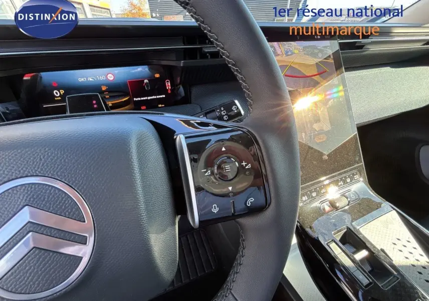Vue intérieure centrée sur le volant et la console centrale brillante du Citroën C5 Aircross Hybrid 2026, ambiance noire élégante.