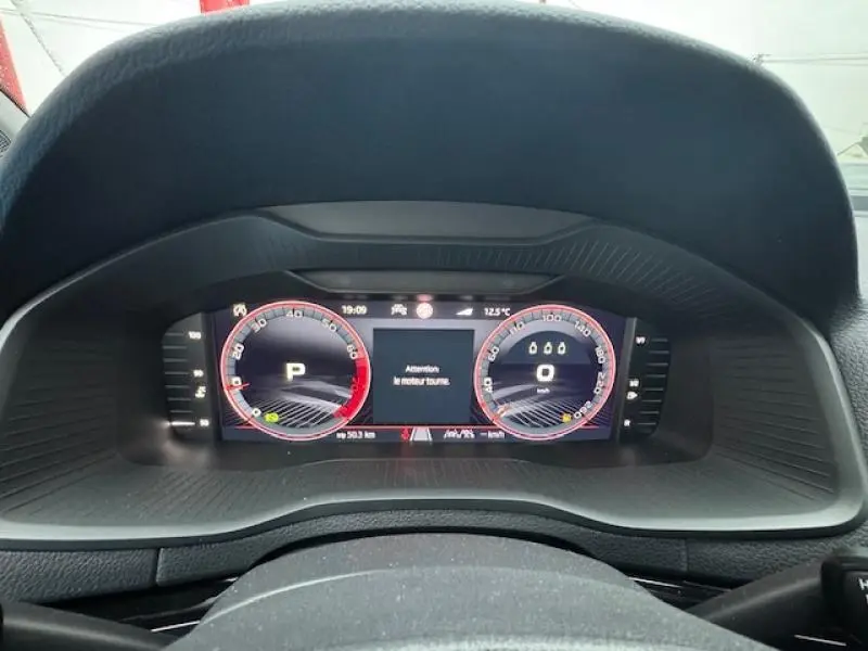 Vue rapprochée du tableau de bord numérique du Skoda Karoq 2025, affichage digital avec alertes et compteurs rouges.