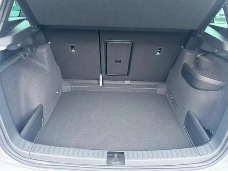 Coffre spacieux du Skoda Karoq gris diamant, vu de l'arrière avec banquette rabattable et rangements latéraux.
