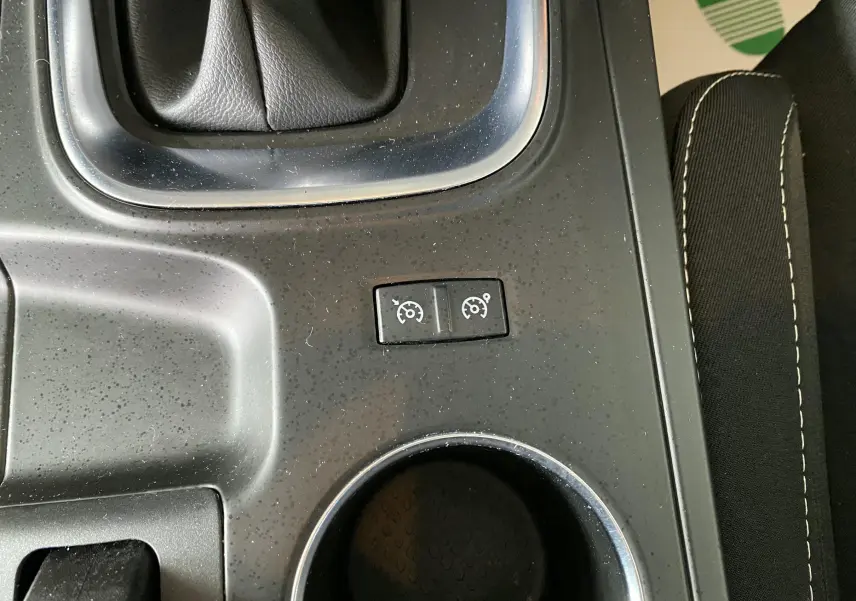 Gros plan sur les commandes de régulateur de vitesse au centre console d'une Renault Mégane IV Business gris, intérieur tissu noir.