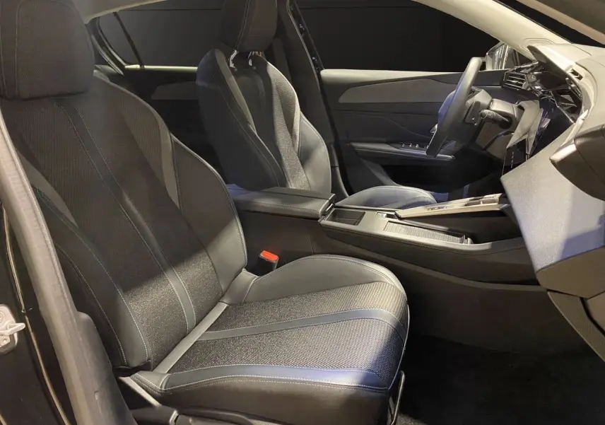 Intérieur noir de la Peugeot 308 2024, vue côté gauche sur les sièges avant en cuir et tissu avec console centrale moderne.
