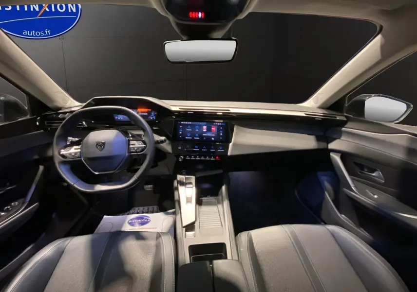 Intérieur noir de la Peugeot 308 2024, vue avant centrée sur le tableau de bord et le volant compact multifonctions.
