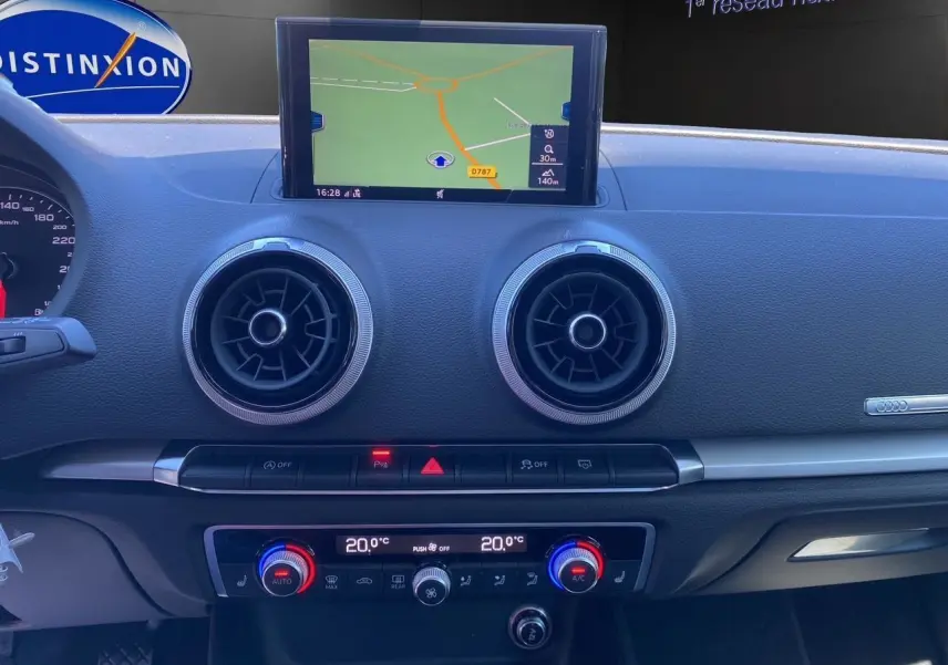 Tableau de bord de l'Audi A3 Sportback 2020 avec écran GPS, aérateurs ronds et commandes climatisation 2 zones visibles de face.