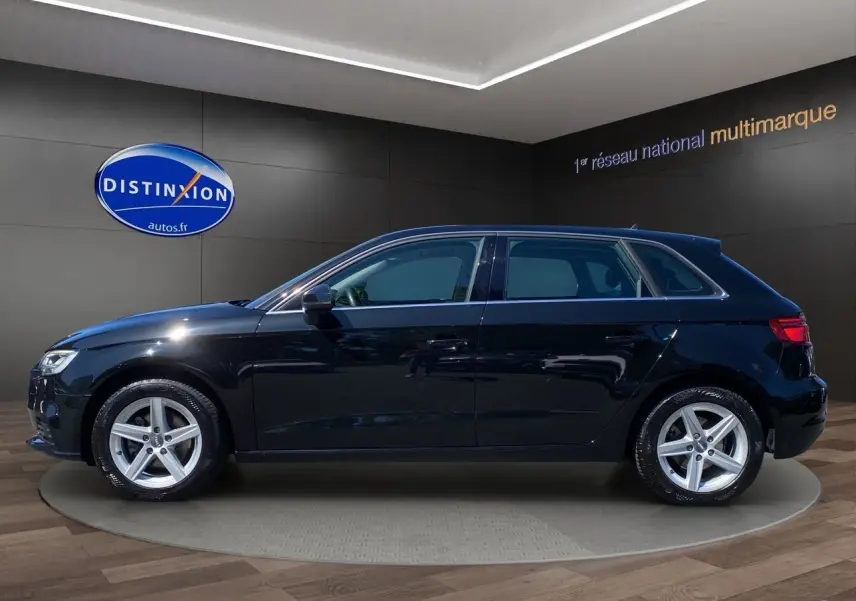 Profil côté gauche d'une Audi A3 Sportback noire 5 portes avec jantes alliage 5 branches en étoile.