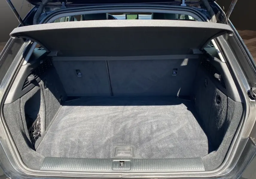 Coffre ouvert vu de l'arrière d'une Audi A3 Sportback noire, montrant un espace de chargement propre et spacieux.