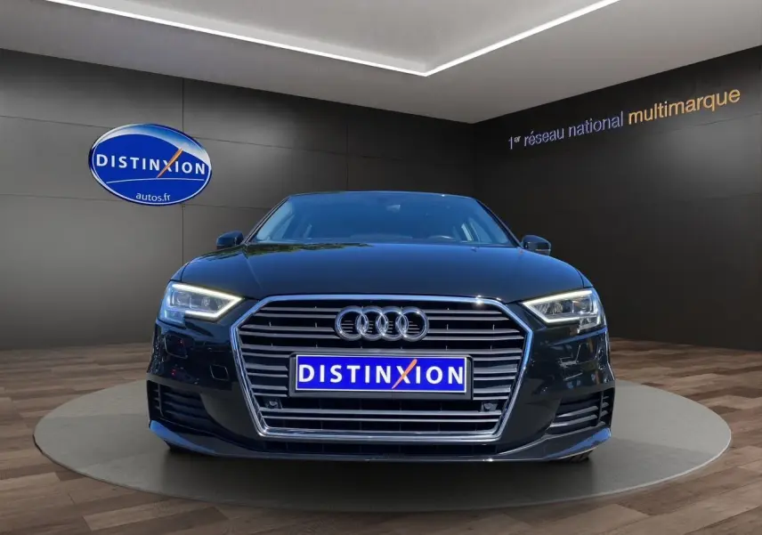 Vue frontale d'une Audi A3 Sportback noire 2020 avec phares LED et calandre chromée dans un showroom.