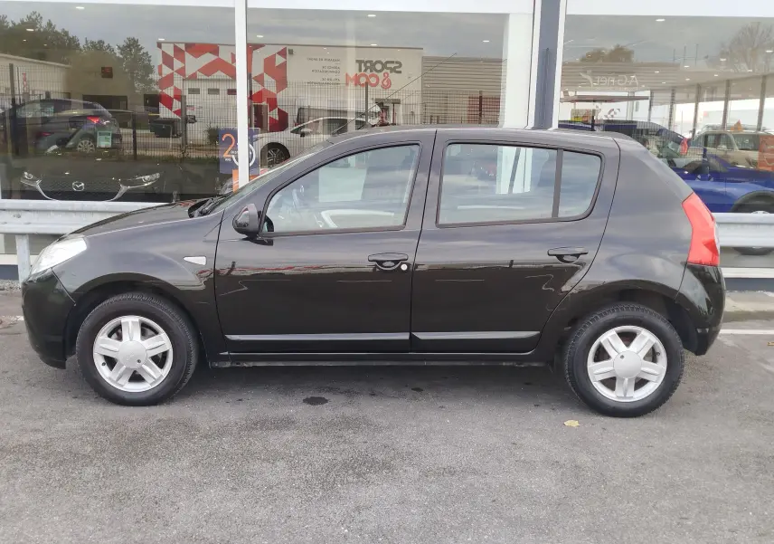 Vue de profil côté gauche d'une Dacia Sandero noire de 2011, cinq portes, avec jantes alliage et rétroviseurs électriques.