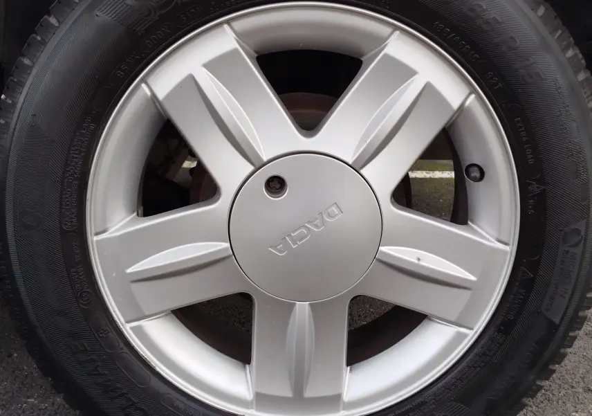 Gros plan sur la jante argentée avec logo Dacia d’une roue de Dacia Sandero noire de 2011.