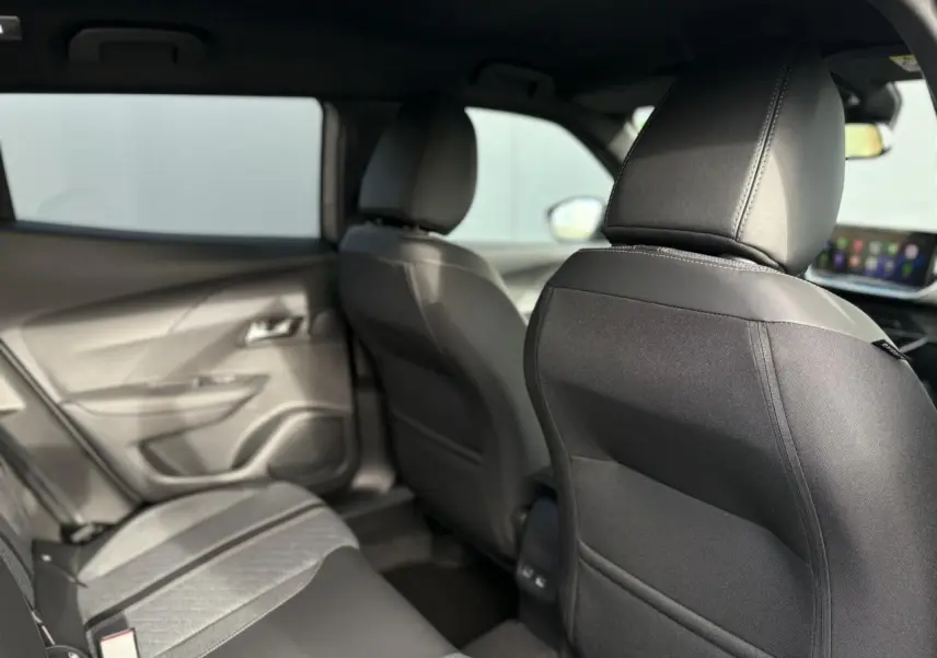 Vue intérieure arrière côté gauche du Peugeot 2008 Hybrid 145 e-DSC6 Allure avec sièges noirs et ciel de pavillon sombre.