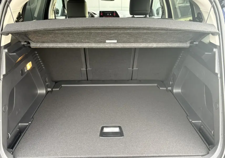 Coffre ouvert vu de l'arrière du Citroën C5 Aircross Bleu Eclipse avec cache-bagages et sièges arrière noirs.