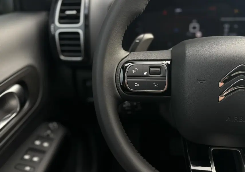 Gros plan sur le volant noir avec commandes intégrées du Citroën C5 Aircross 2025, intérieur en Alcantara noir.