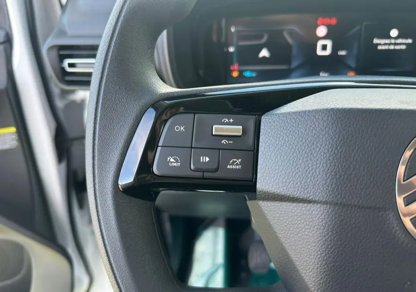 Gros plan sur les commandes gauche du volant noir du Citroën Berlingo 2026 avec affichage numérique en arrière-plan.