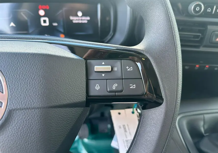 Gros plan sur les commandes du volant côté droit du Citroën Berlingo blanc Icy avec écran numérique en arrière-plan.