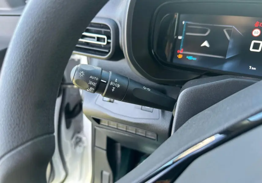 Gros plan sur la commande des feux et clignotants à gauche du volant dans l’habitacle du Citroën Berlingo blanc Icy.
