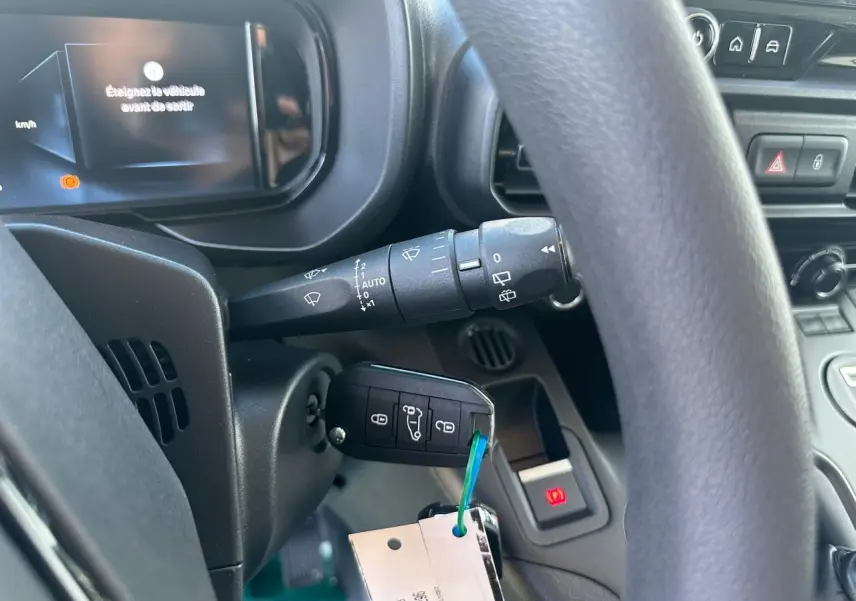 Vue rapprochée du tableau de bord côté conducteur du Citroën Berlingo blanc, avec clé insérée et affichage numérique.