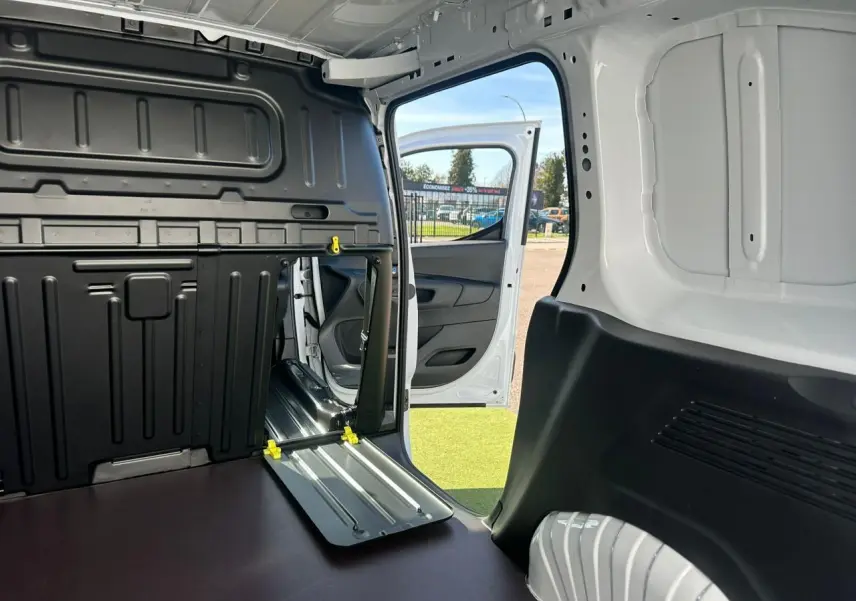 Vue intérieure du coffre du Citroën Berlingo blanc Icy avec porte latérale droite ouverte et cloison partielle rabattue.