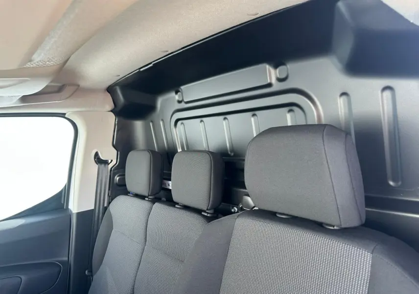 Vue intérieure côté droit montrant les sièges avant noirs et la cloison métallique du Citroën Berlingo III Van Blanc Icy.