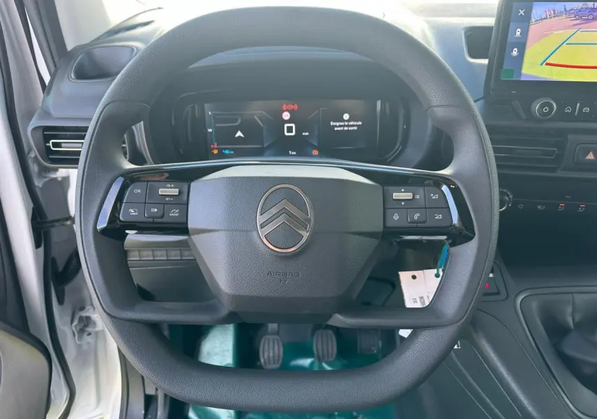 Vue intérieure centrée sur le volant noir du Citroën Berlingo blanc Icy avec tableau de bord numérique et écran tactile.