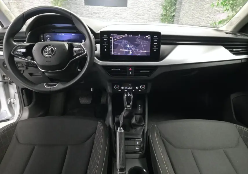 Vue intérieure avant du Skoda Kamiq 2023, tableau de bord noir avec écran tactile et volant multifonctions.