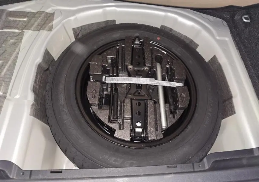 Vue plongeante sur la roue de secours et les outils de bord dans le coffre d'une Skoda Kamiq gris 2023.