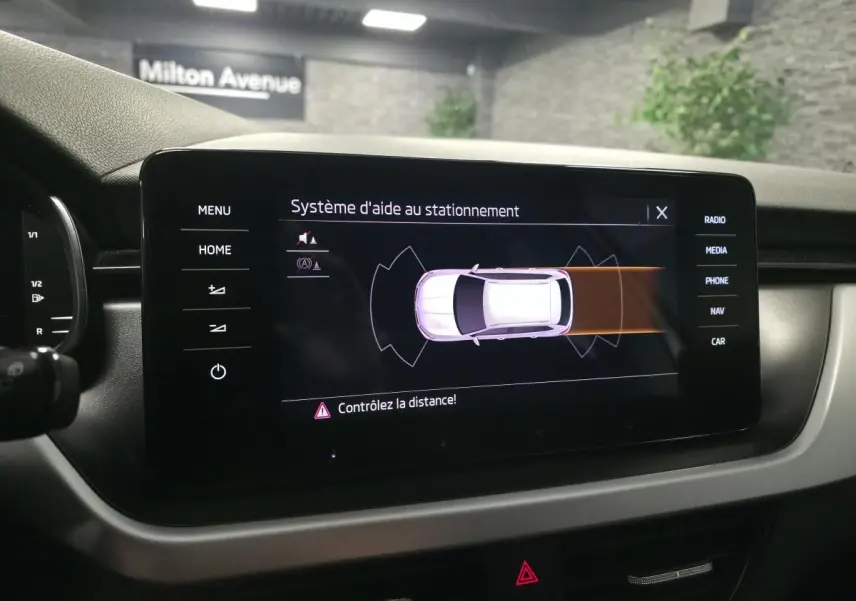 Écran tactile intérieur du Skoda Kamiq 2023 montrant l’aide au stationnement avec alertes de distance.