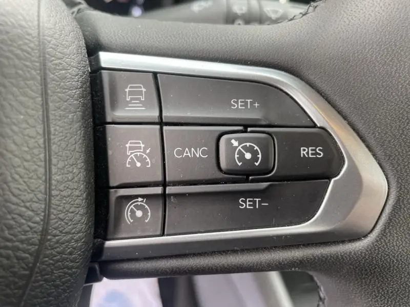 Gros plan sur les commandes de régulateur de vitesse au volant noir du Jeep Compass blanc 2023, version Limited.