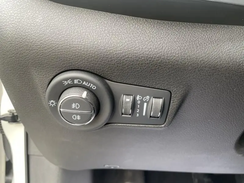 Gros plan sur les commandes d’éclairage intérieures du Jeep Compass blanc 2023, avec réglages de phares et niveaux de luminosité.