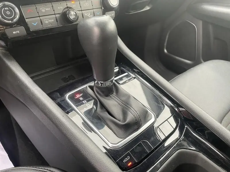 Gros plan sur la console centrale du Jeep Compass 2023 avec levier de boîte auto noir et commandes de climatisation visibles.