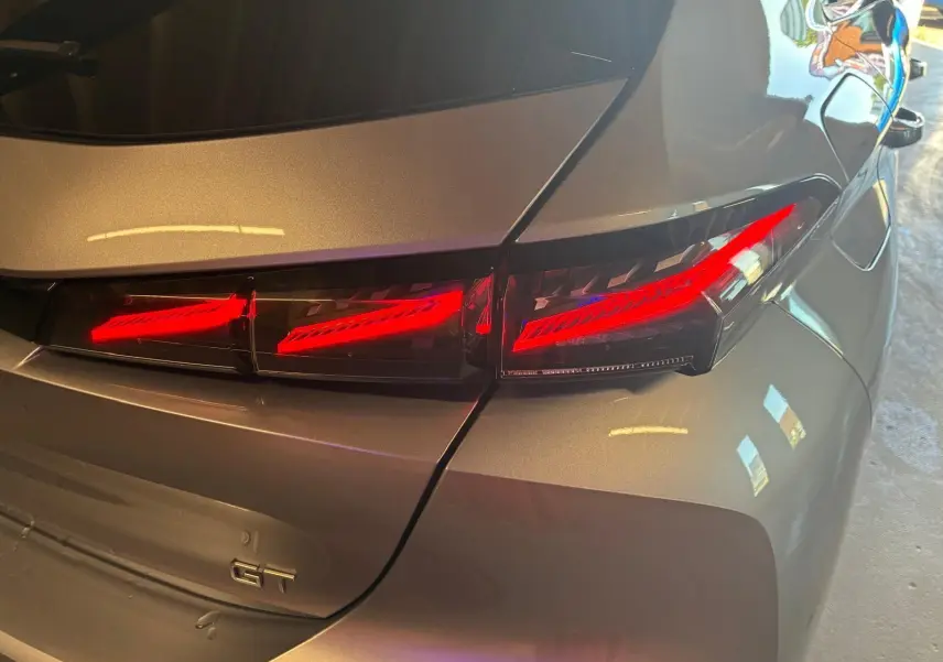 Feu arrière droit allumé sur Peugeot 308 gris 2025, version 1.2 HYBRID 136 E-DCS6 GT, vue rapprochée arrière.