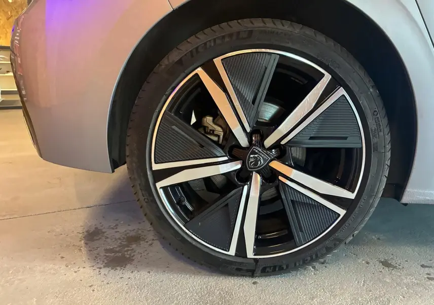 Gros plan sur la roue avant droite de la Peugeot 308 gris 2025, mettant en valeur la jante noire et argentée au design moderne.