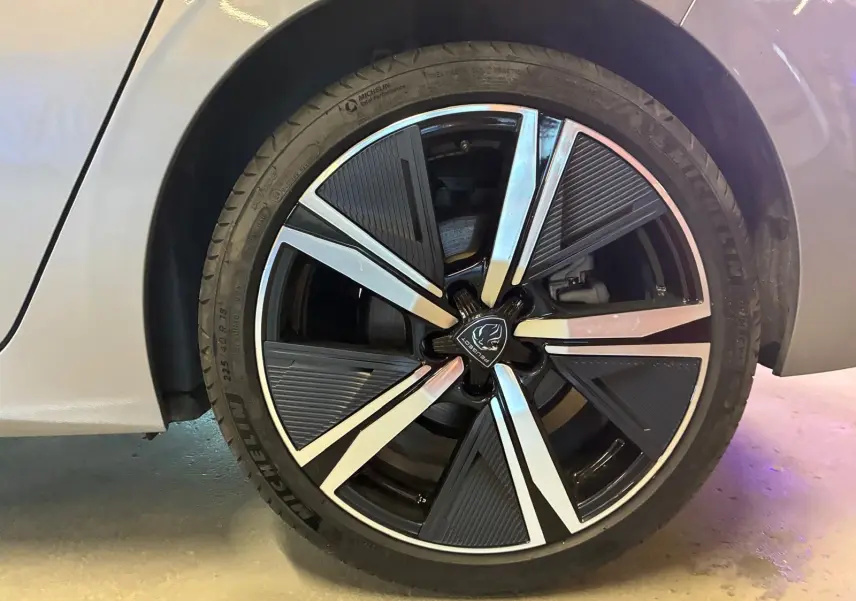 Gros plan sur la roue avant droite gris métallisé d'une Peugeot 308 1.2 Hybrid 136 E-DCS6 GT avec jante noire et argent.