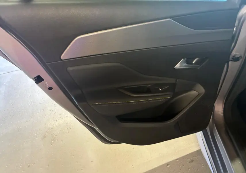 Vue rapprochée de la porte arrière gauche gris foncé de la Peugeot 308 1.2 Hybrid 2025 avec garniture noire et poignée argentée.