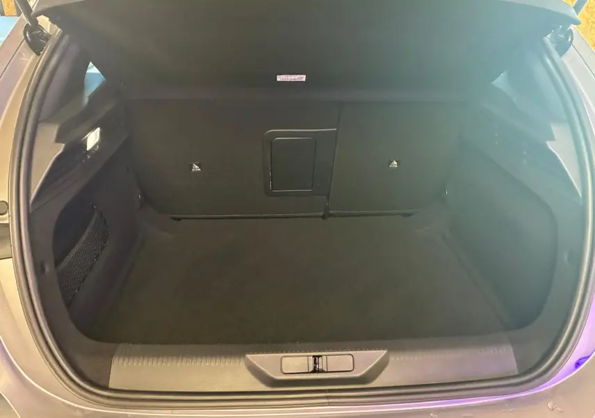 Coffre ouvert de la Peugeot 308 gris, vue de dessus montrant l’espace de rangement intérieur vide.