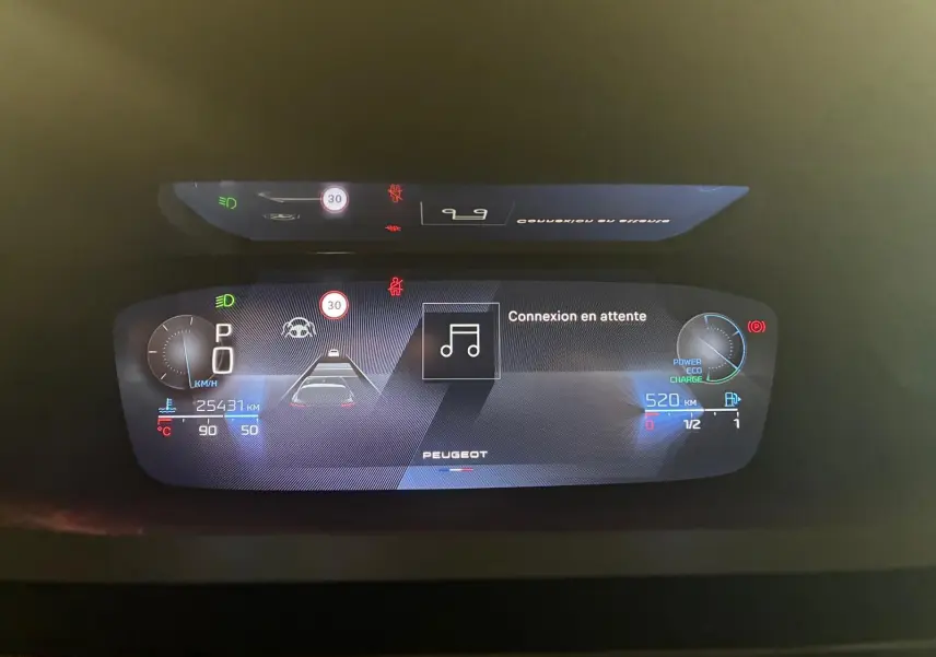 Tableau de bord numérique de la Peugeot 308 gris, affichant la vitesse, autonomie et alertes en vue frontale rapprochée.