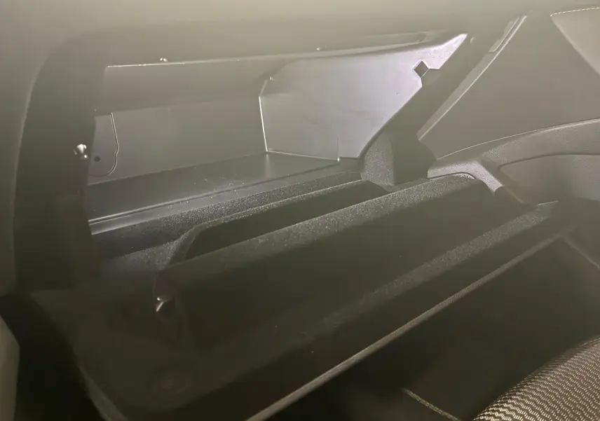 Vue rapprochée de la boîte à gants ouverte du Peugeot 308 gris 1.2 Hybrid 136 E-DCS6 GT, intérieur noir.