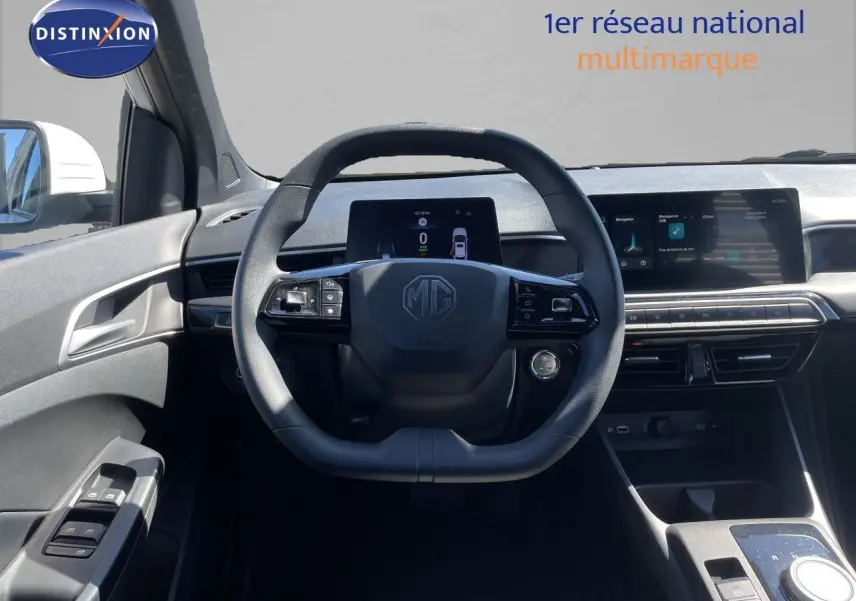 Vue intérieure centrée sur le volant MG d'une MG3 1.5L Hybrid+ blanche, avec tableau de bord digital et écran tactile.