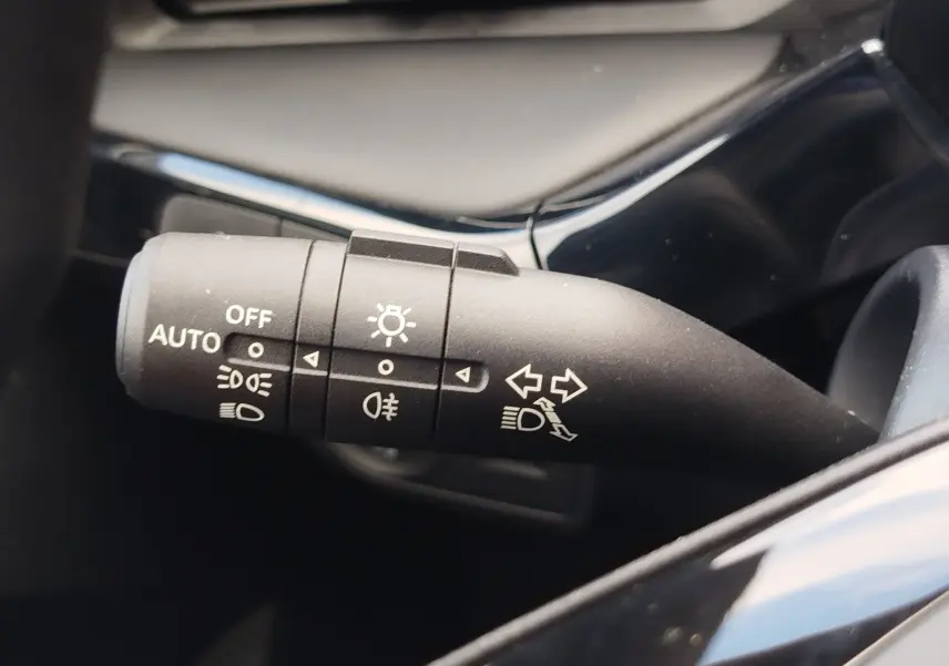 Gros plan sur la commande des feux et clignotants du MG3 1.5L Hybrid+ 2025, intérieur noir brillant.